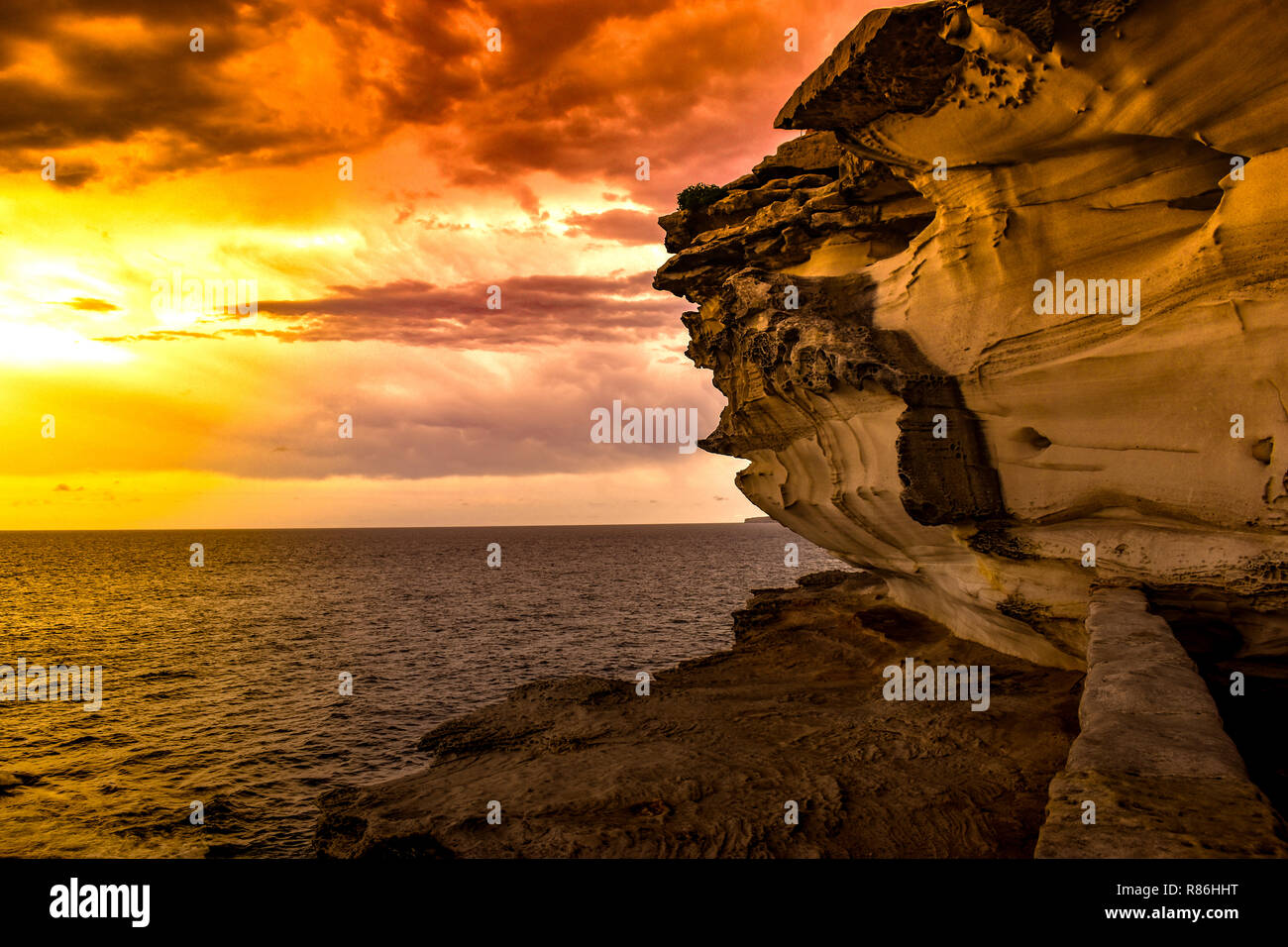 This beautiful scene of rocks and mountain on beach was captured during the sunset in a Stanwell Park Sydney NSW Australia. Stock Photo