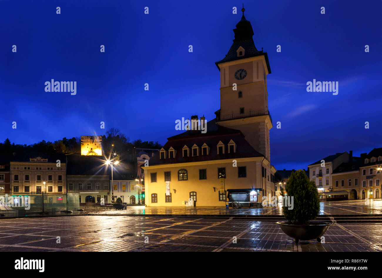 The Council Square during rain in Brasov, Romania. View with famous buildings in evening and public lights. Stock Photo