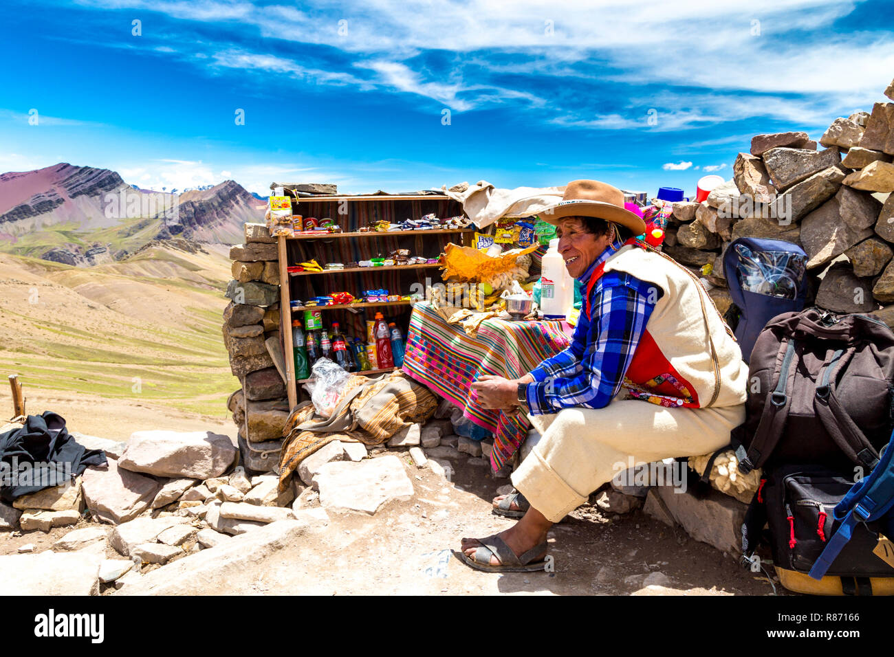 Peruvian man dressed in traditional clothing with his shop, selling coca tea in the Rainbow Mountain (Vinicunca), Peru Stock Photo