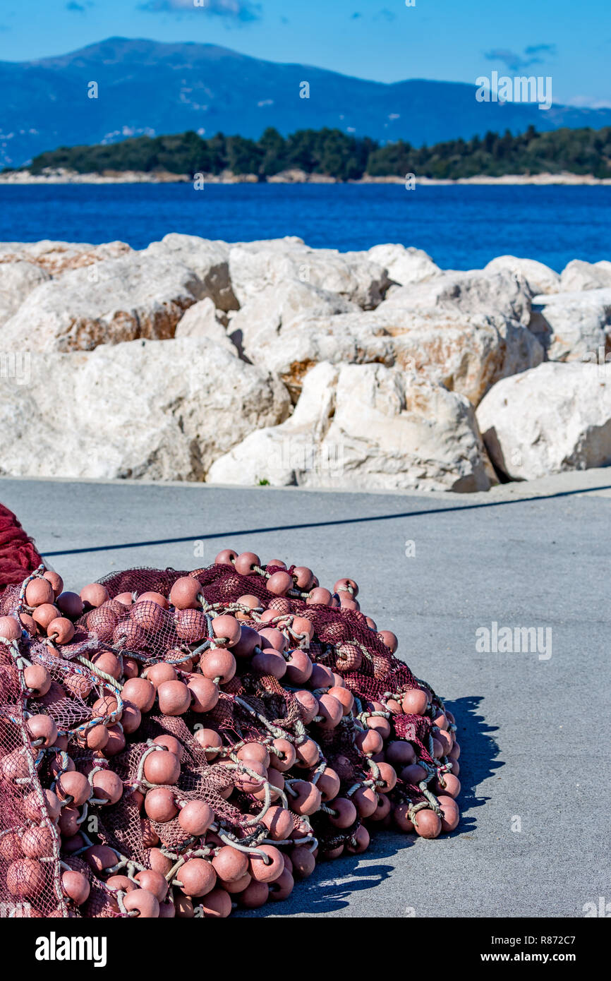 Close-up on pink fishing net with buoys piled and drying near the water edge at the port of Corfu, Kerkyra island, Greece in a bright sunny spring day Stock Photo