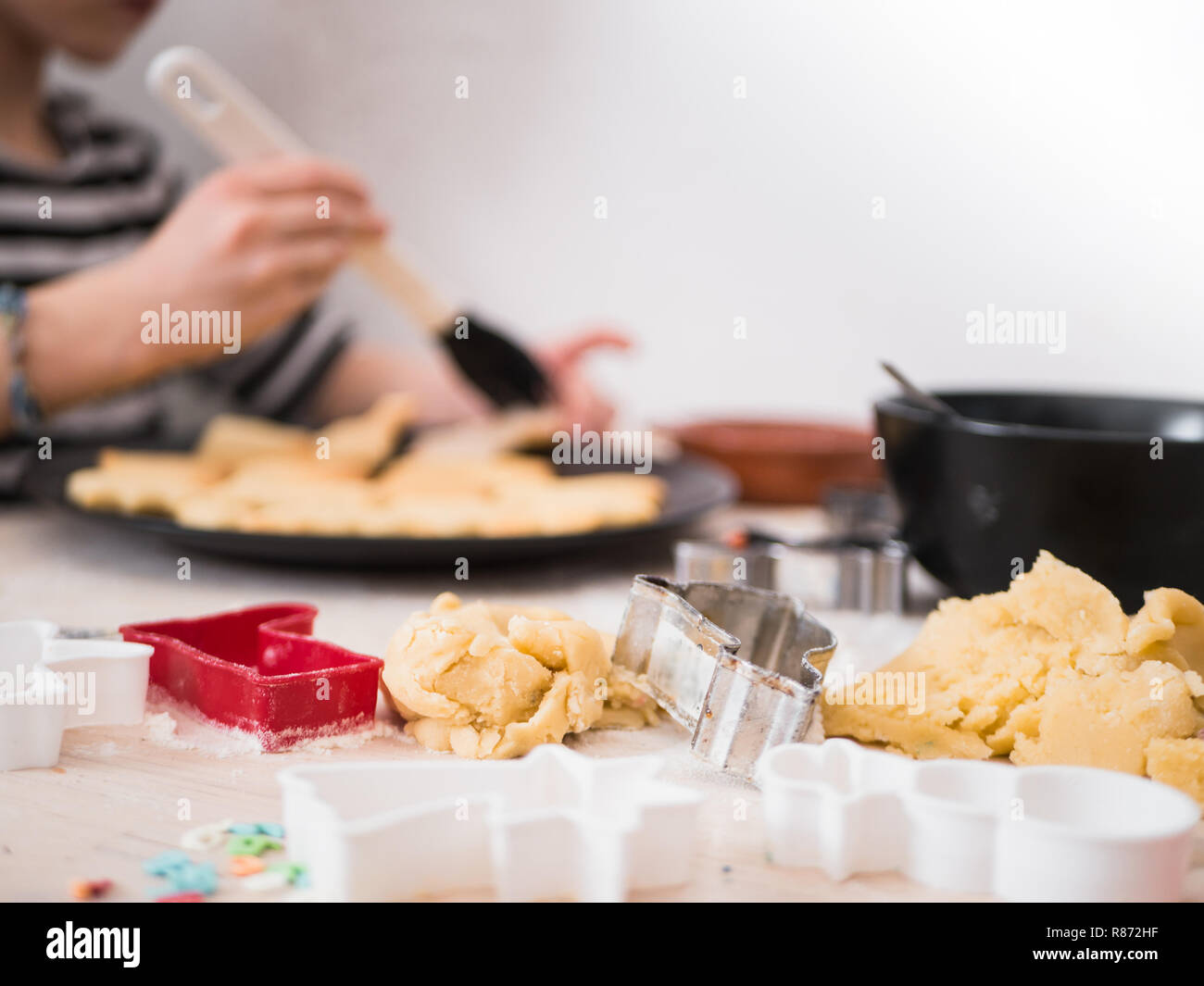 Christmas bakery: Little Girl painting cookie dough with sugar glazing, decorating Stock Photo