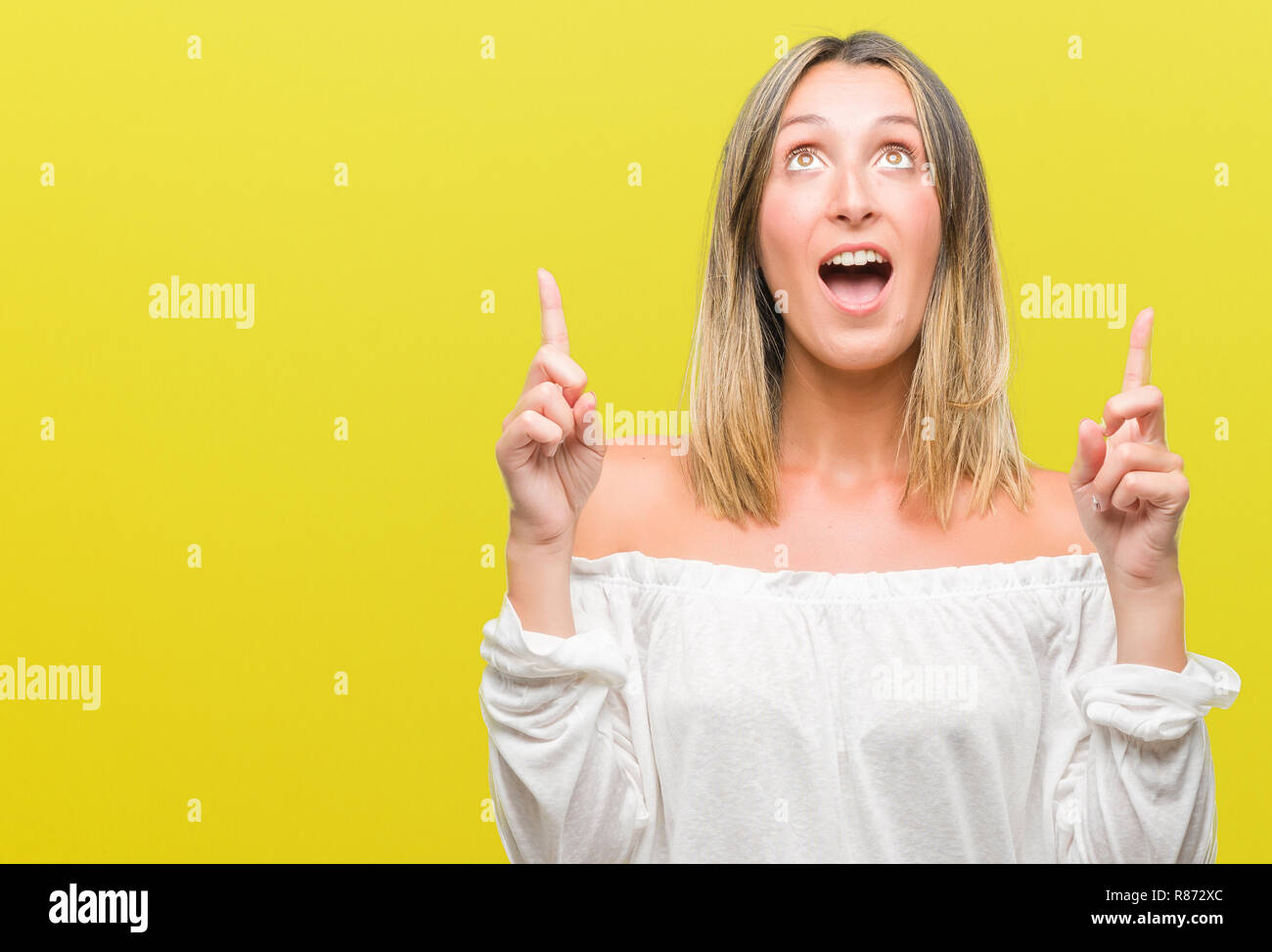 Young beautiful woman over isolated background amazed and surprised ...