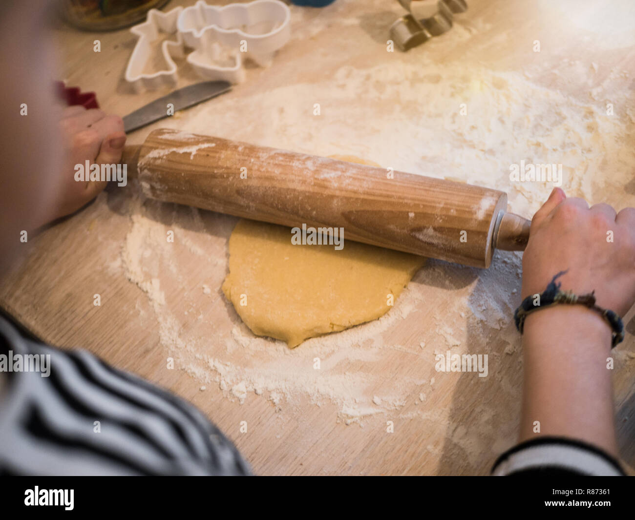 Christmas bakery: Little Girl rolling cookie dough, over the shoulder shot Stock Photo
