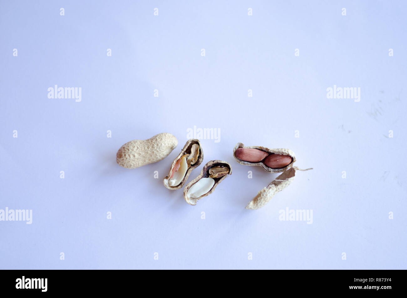 Peanuts on display on white background. One of them cracked with one bad and one good peanut. Stock Photo