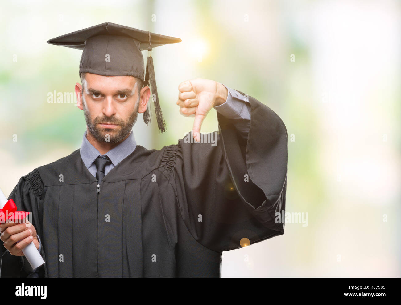 Young handsome graduated man holding degree over isolated background ...