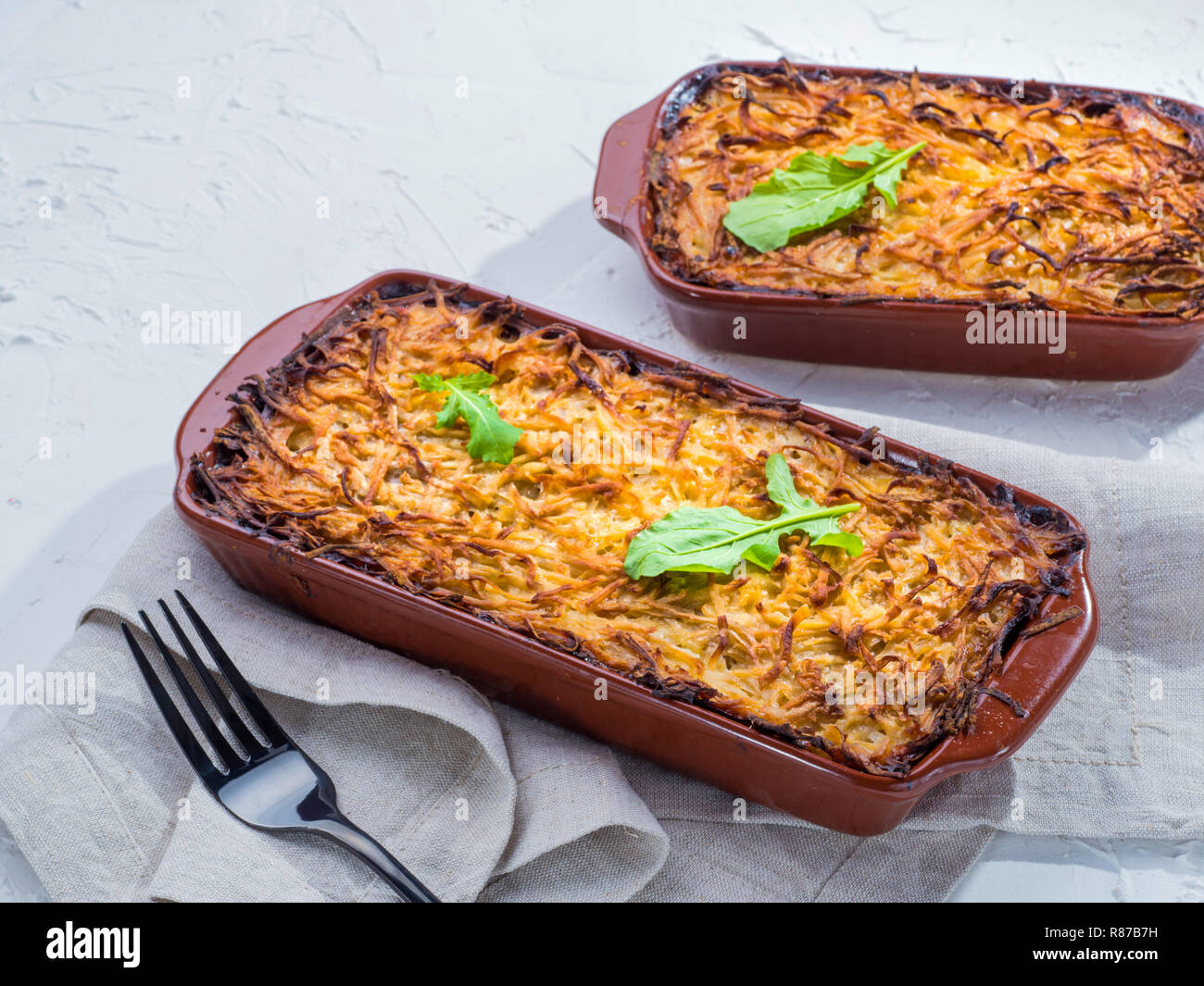 Close up view of appetizing potato casserole with fish, eggs and cream. Potato casserole in serving baking dish on white concrete background Stock Photo