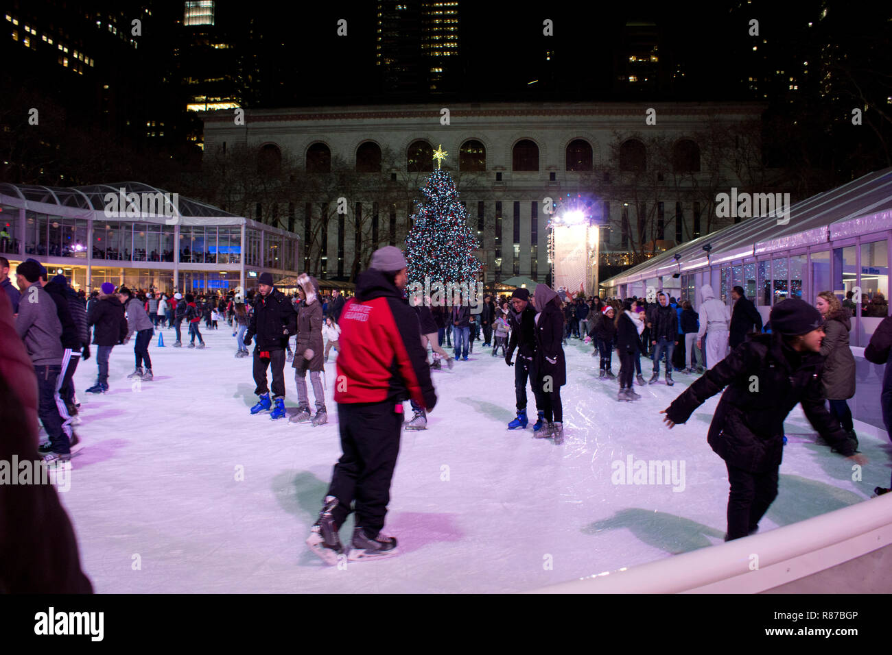 Citi Pond ice skating rink at Bryant Park in Manhattan with Christmas Tree on display. People ice skating at the rink at Bryant Park in New York City. Stock Photo