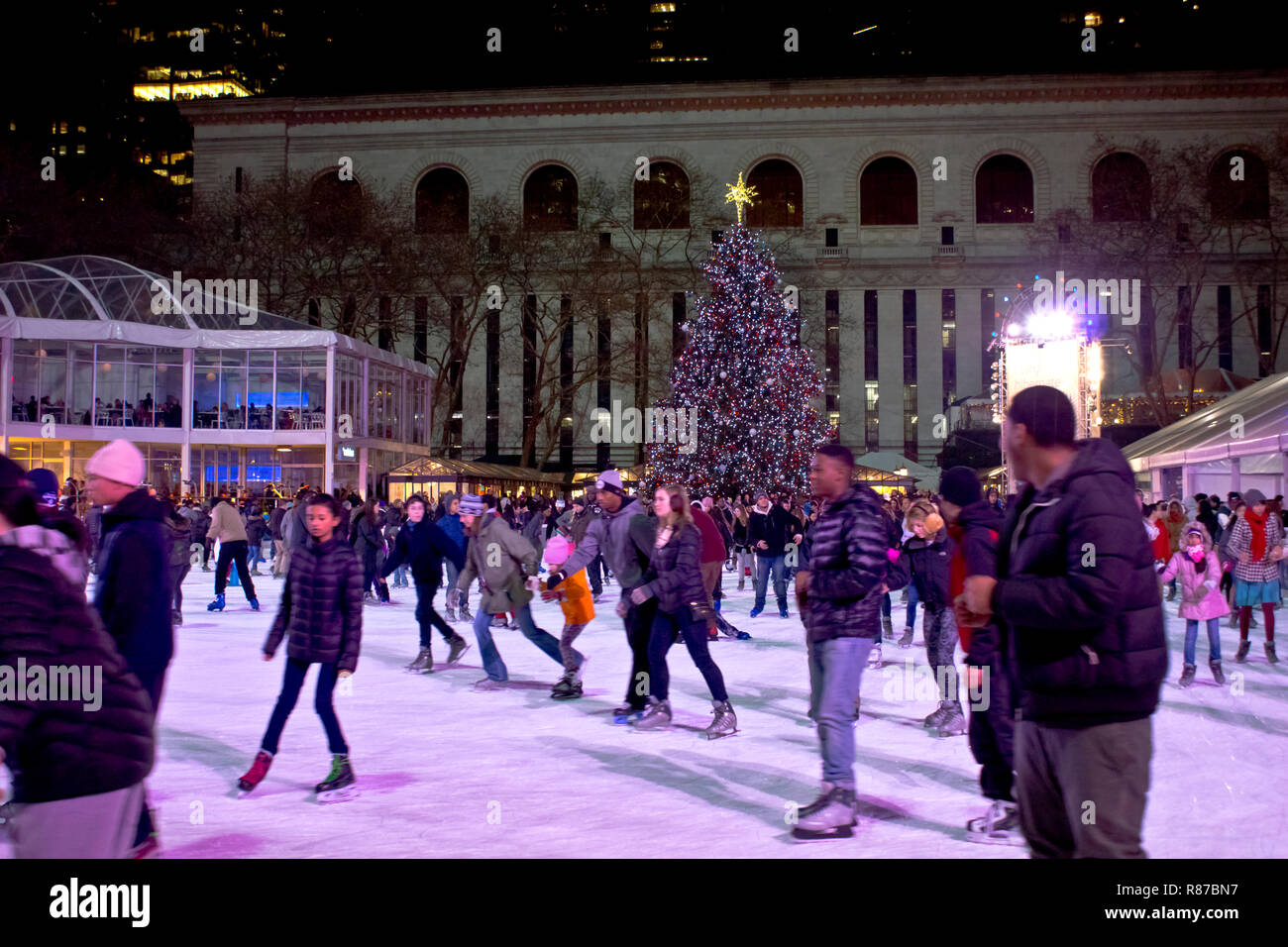 Citi Pond ice skating rink at Bryant Park in Manhattan with Christmas Tree on display. People ice skating at the rink at Bryant Park in New York City. Stock Photo