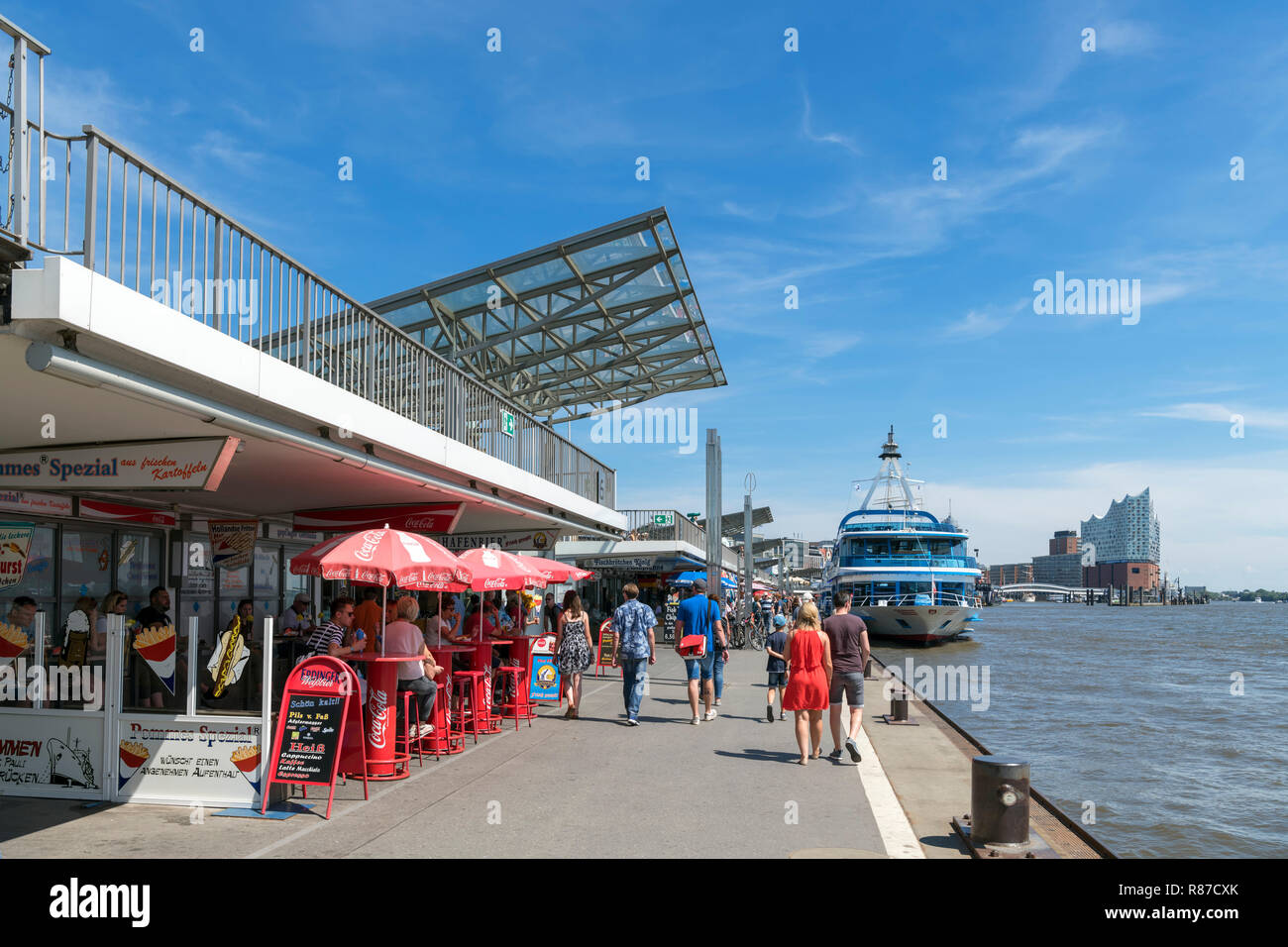Cafes and boats moored along the St. Pauli Landungsbrücken (St Pauli Piers), Hamburg, Germany Stock Photo