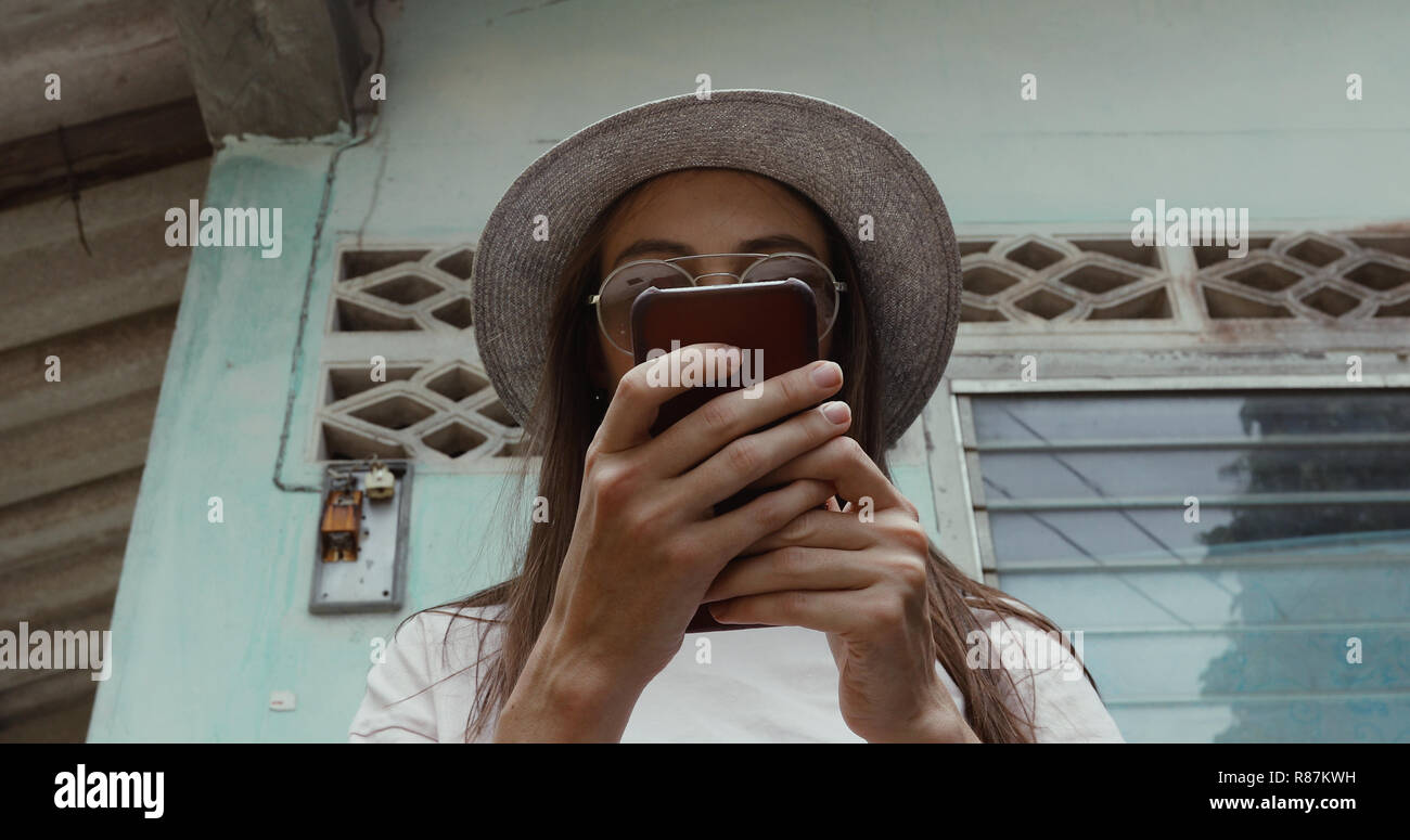 Stylish female using smartphone near shabby building Stock Photo