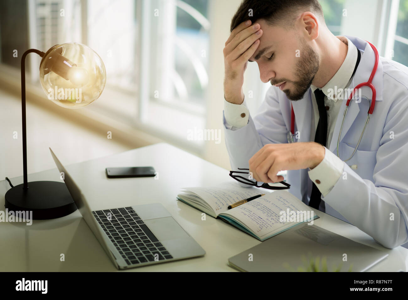 Doctors are making serious faces and stressed about work. The doctor is feeling a headache at work and feeling stressed in treating the patient. Stock Photo