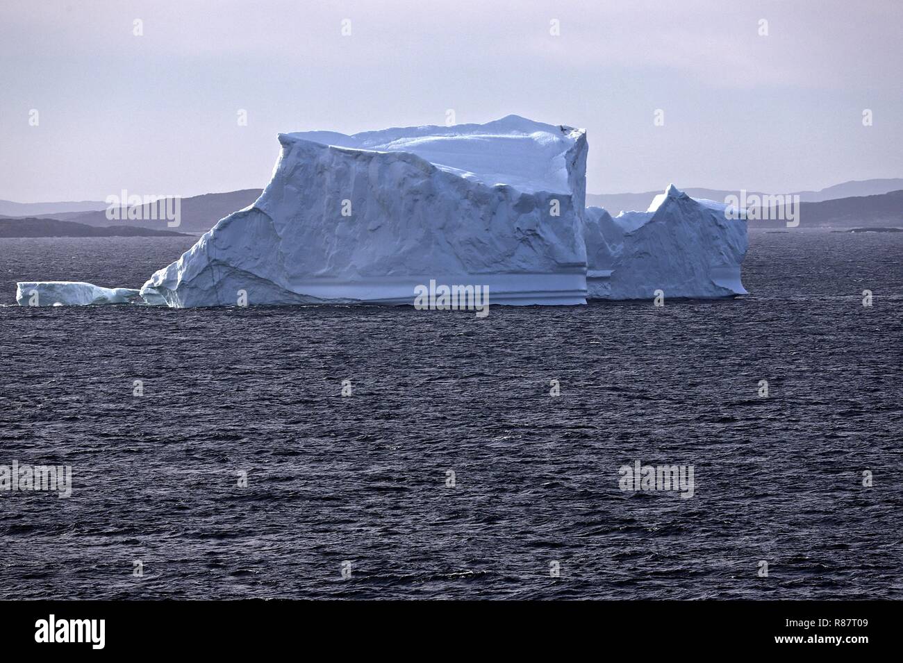 Grönland Diskobucht Vor der Küstenlinie hebt sich der sonnenbeschienene Eisberg prächtig ab Stock Photo