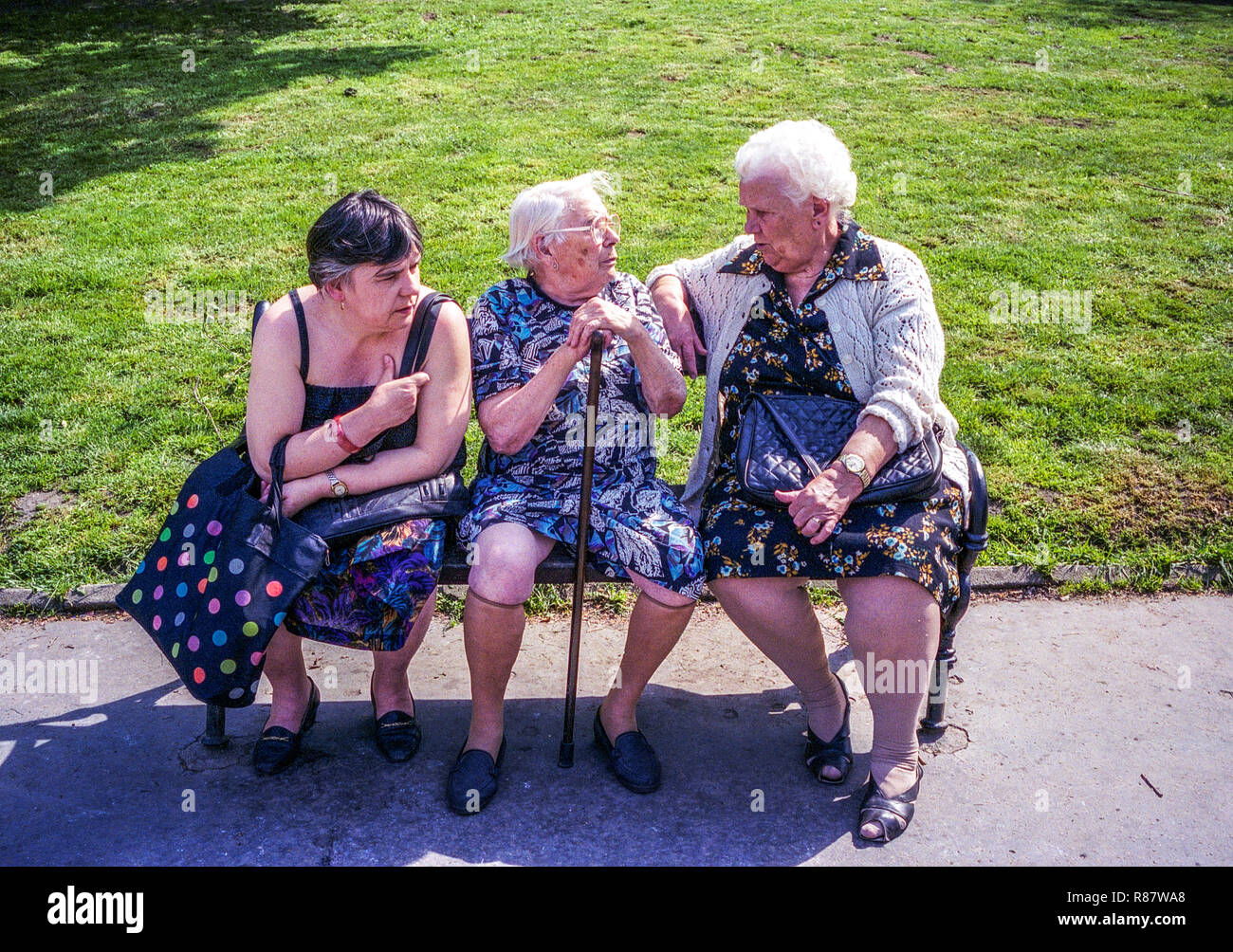 Three elderly women on a bench, senior people sitting on a bench in a park stick Czech Republic Old women talking seniors older generation Stock Photo