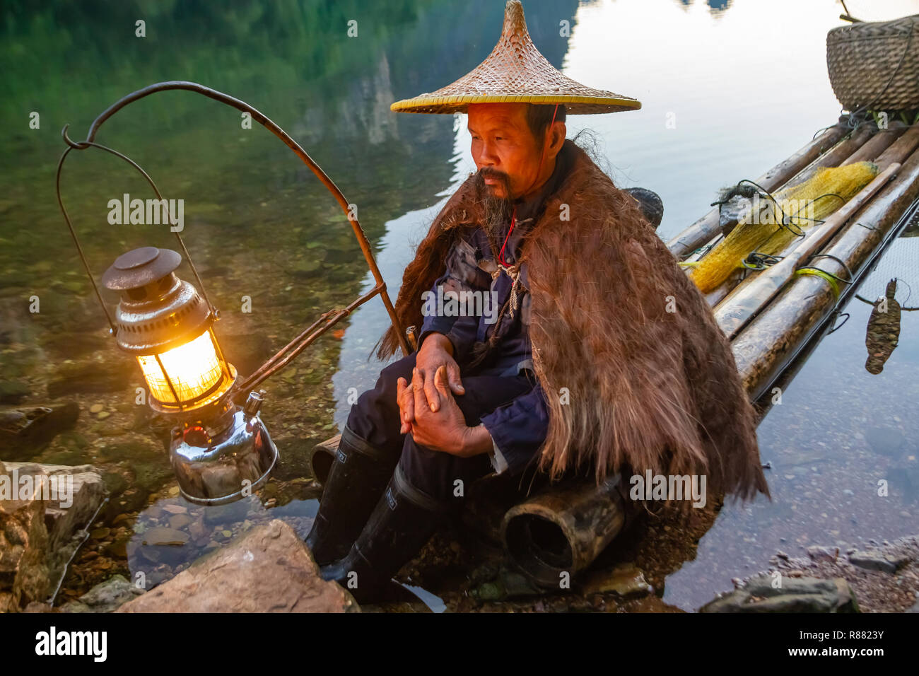 Chinese cormorant fisherman on raft in lake with pipe and fishing gear in  Guilin, China Stock Photo - Alamy