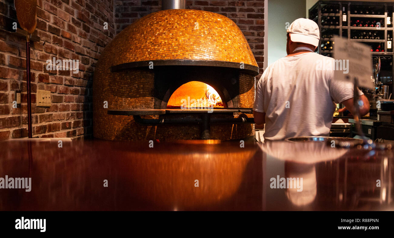 A chef is putting a handmade fresh pizza in a wood burning brick oven pizza. Stock Photo