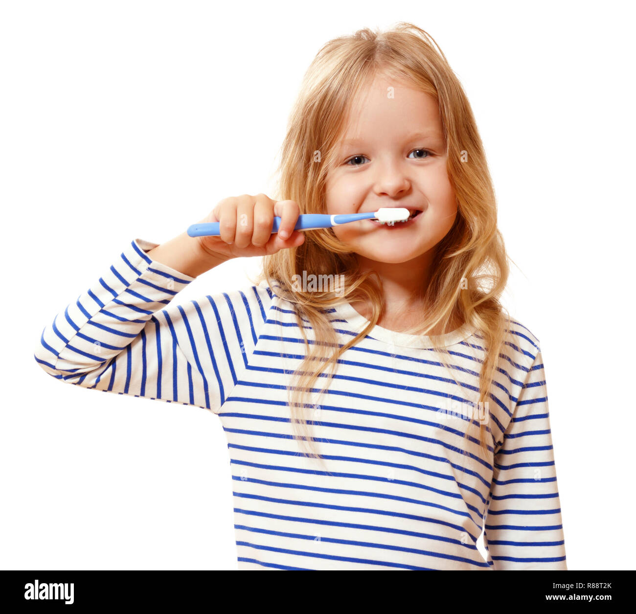 A little girl in striped pajamas is brushing her teeth with a toothbrush. The concept of daily hygiene. Isolated on white background Stock Photo
