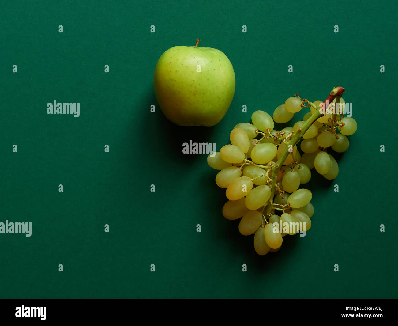 Green apple and bunch of green grapes isolated in studio with a green background viewed from above Stock Photo
