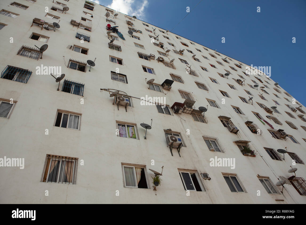 Detail of apartment building facade with windows and satellite dishes ...