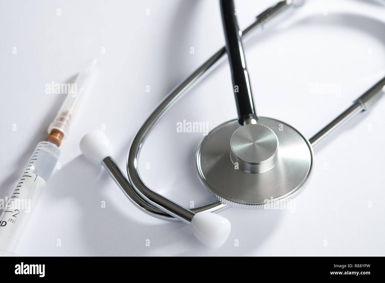 stethoscope on white table with syringe Stock Photo