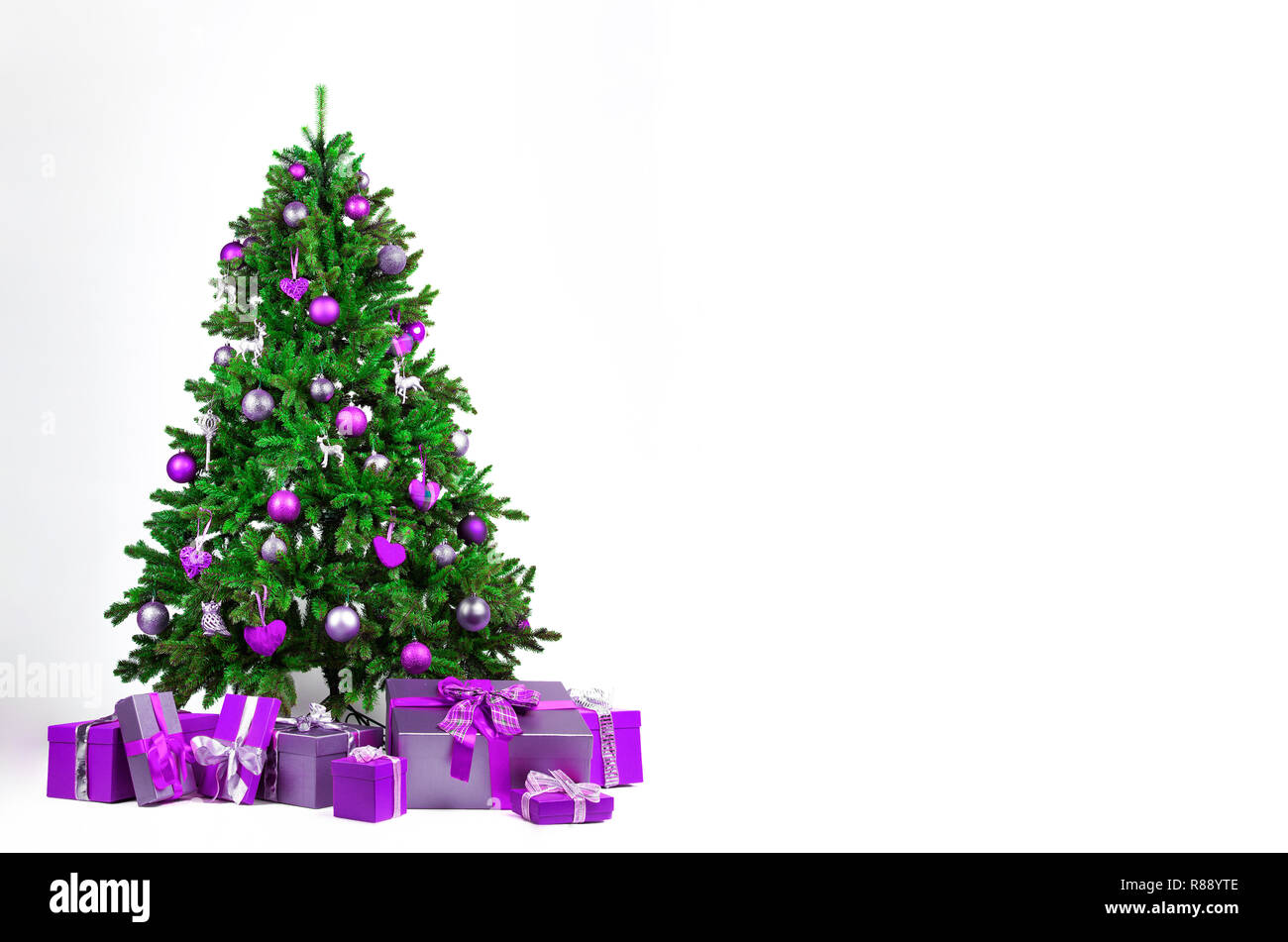 Christmas background. White Christmas fir tree with purple Christmas  decorations on a purple background Stock Photo