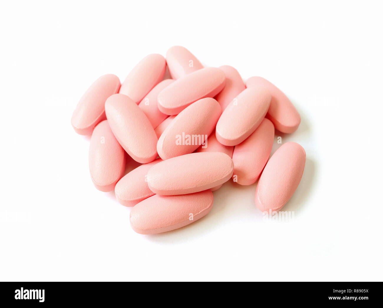 Pile of light pink color oval shaped pills isolated on white background