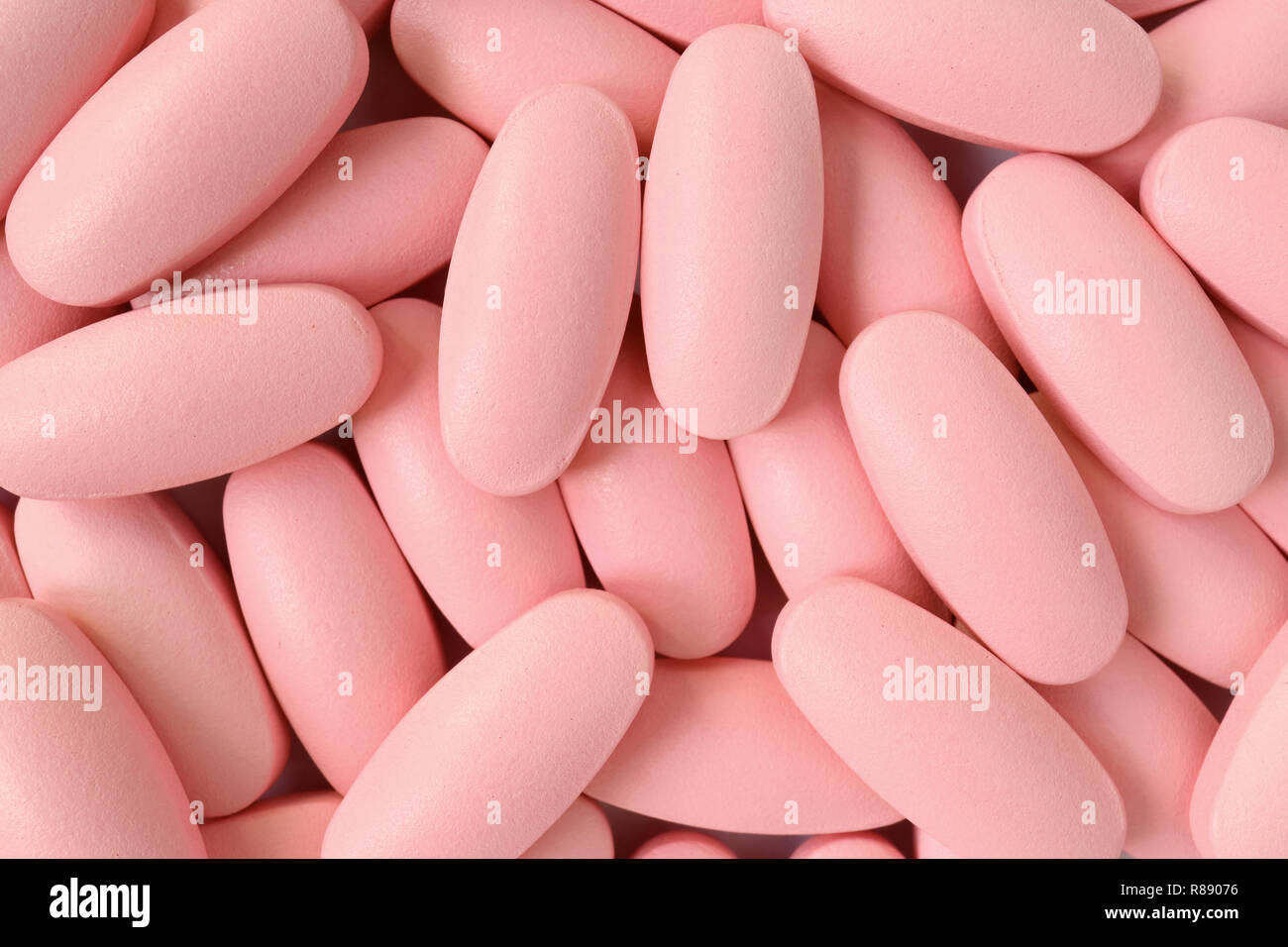 Top view of heap of light pink color oval shaped pills for background