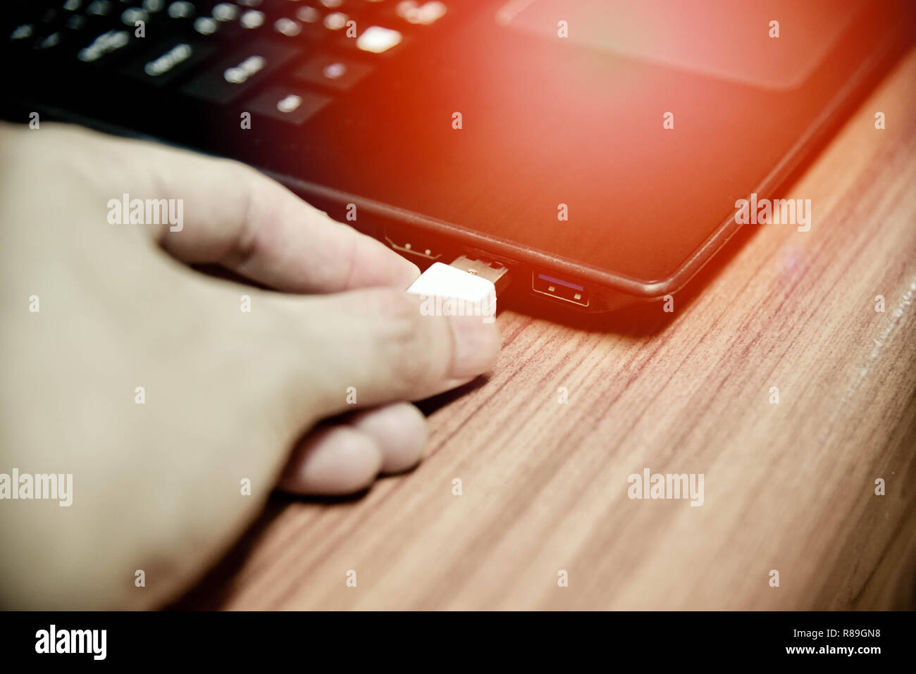 hand plugging usb cable in notebook device / white electronics cable in usb port on computer accessories Stock Photo
