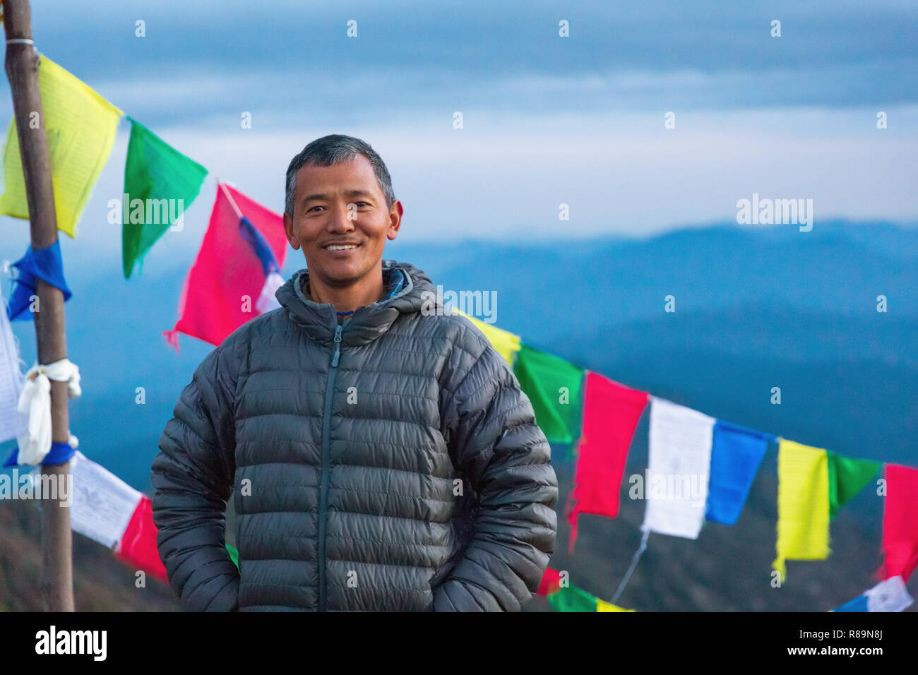 Portrait of smiling Sherpa man and prayer flags in Annapurna Himal, Nepal, Himalayas, Asia Stock Photo