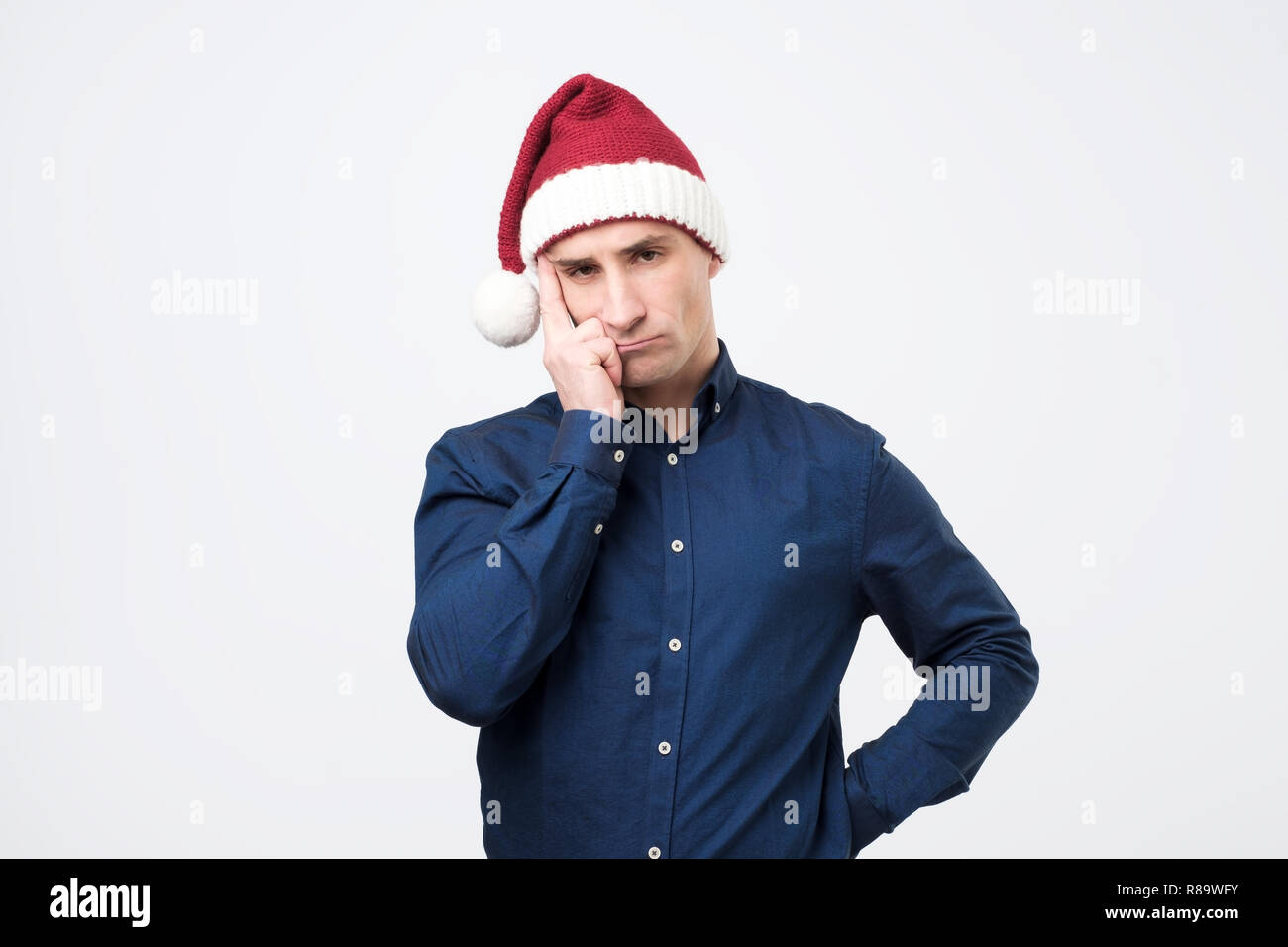 Portrait of sad man in red santa claus hat. Stock Photo