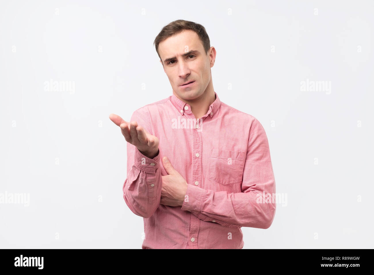 Sad unhappy young man in pink shirt has grumpy expression after quarrel with wife. Stock Photo