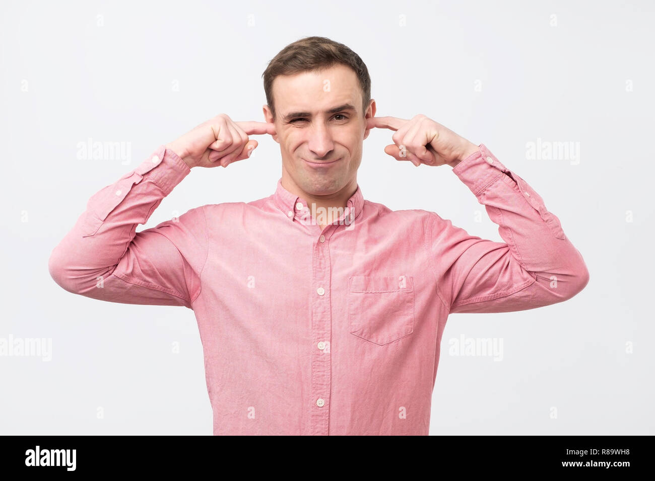 Mature man with annoyance closing ears with fingers not wanting to hear something. Stock Photo