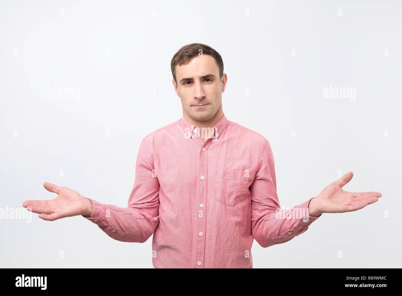 I do not know. Young man being at a loss, showing helpless gesture with arm and hands Stock Photo