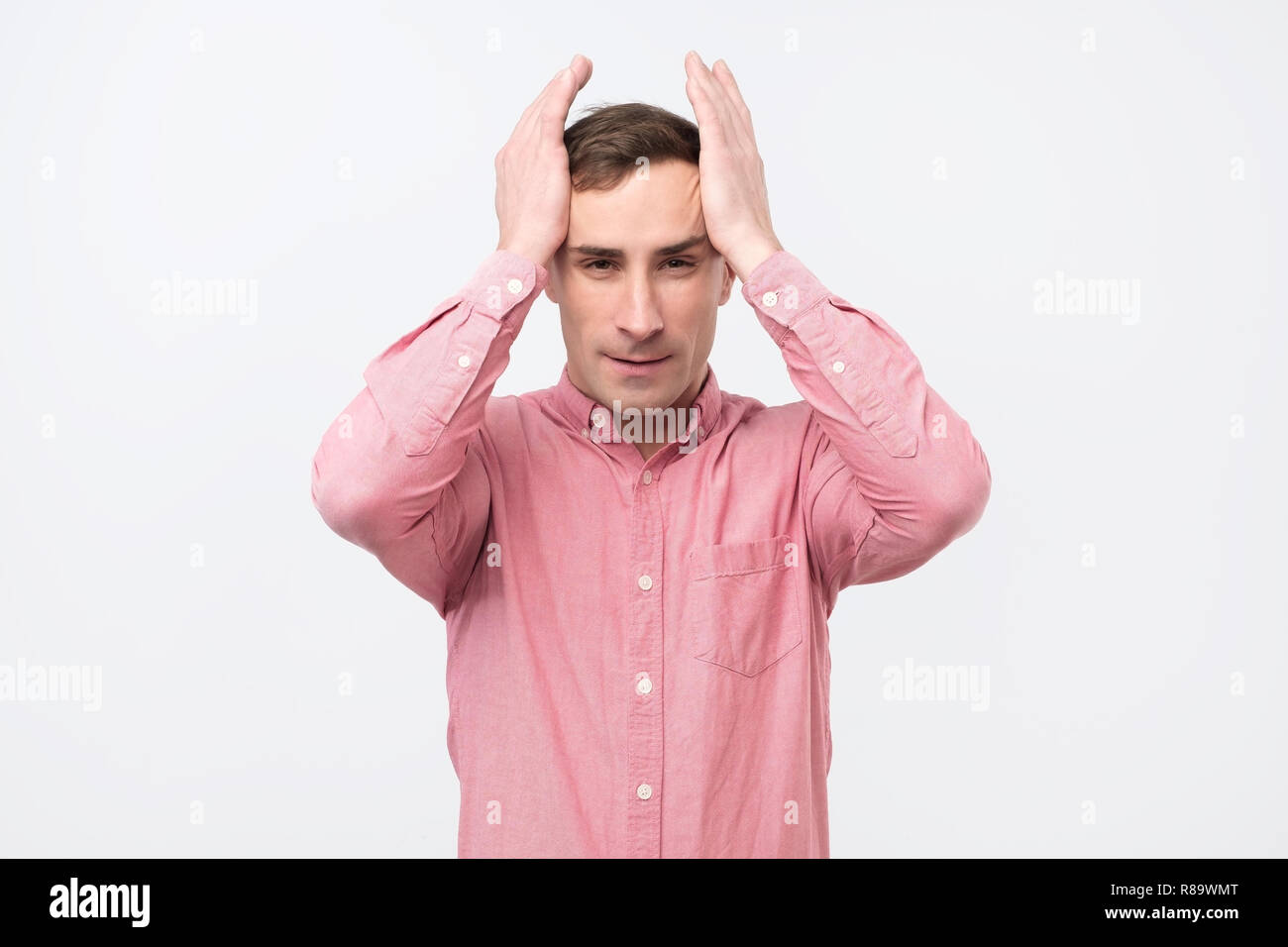 Mature man with hysterical expression holding his hands on head over white background. Stock Photo