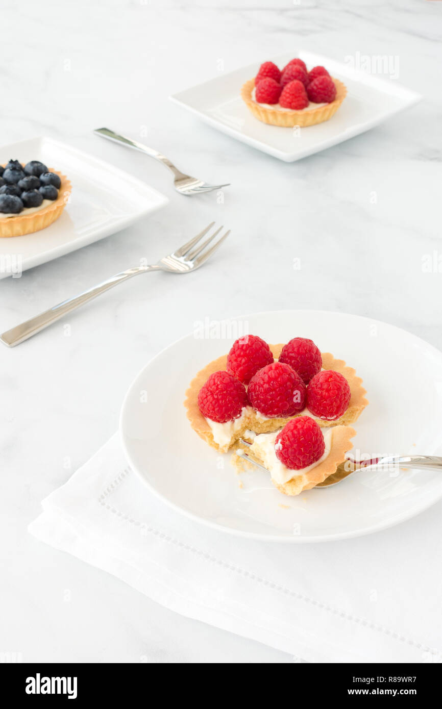 Homemade blueberry and raspberry tartlets filled with vanilla cream on