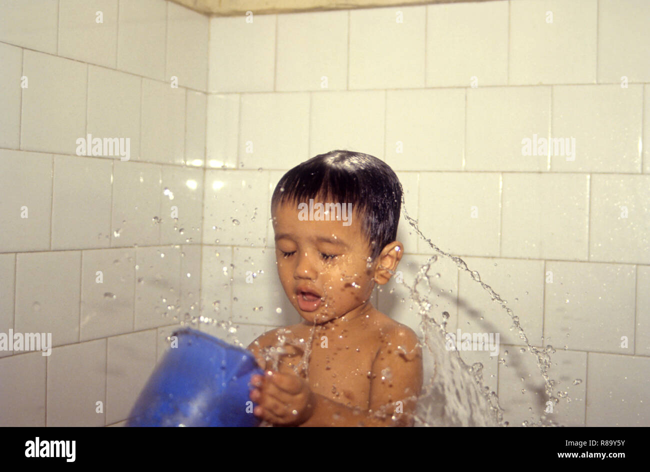 boy splashing water by tub on himself and bathing, Ishan 3 year MR Stock Photo
