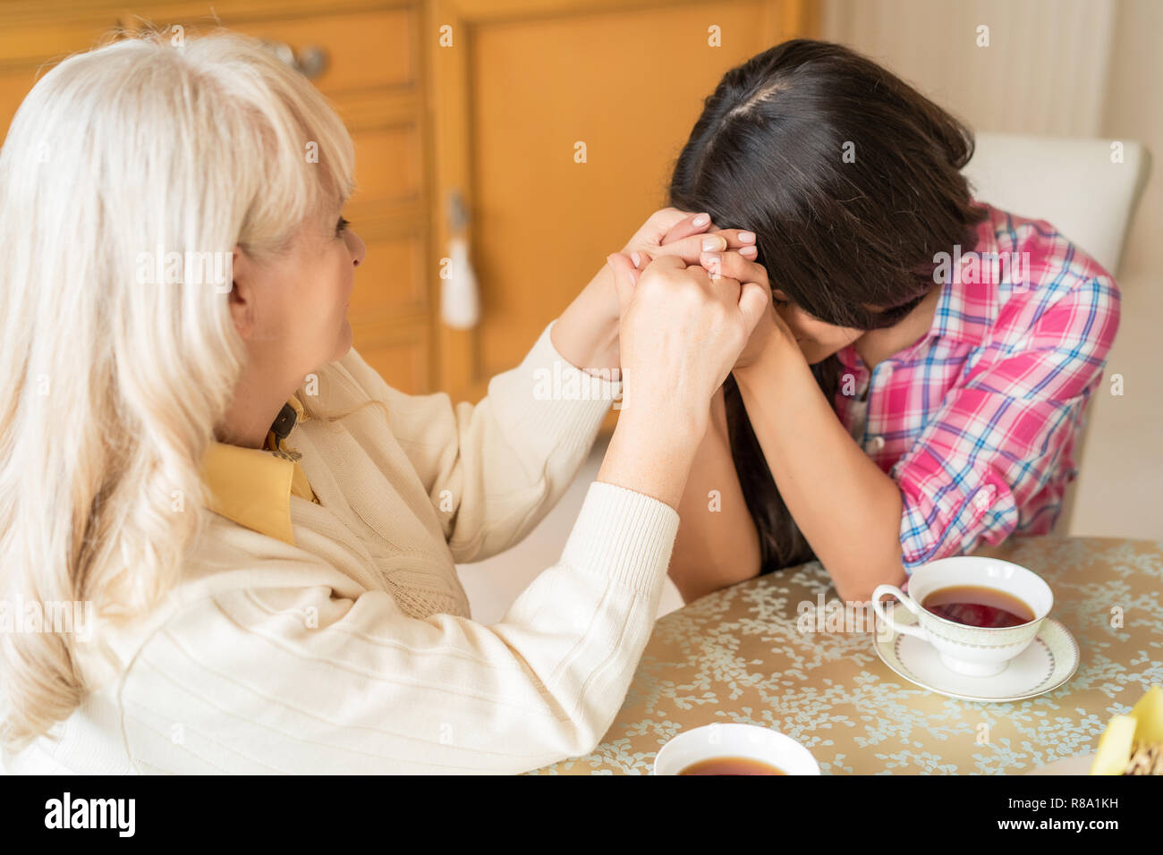 Charming Daughter Asks For Blessing From Her Elderly Mother At The Table. Thankfulness Stock Photo