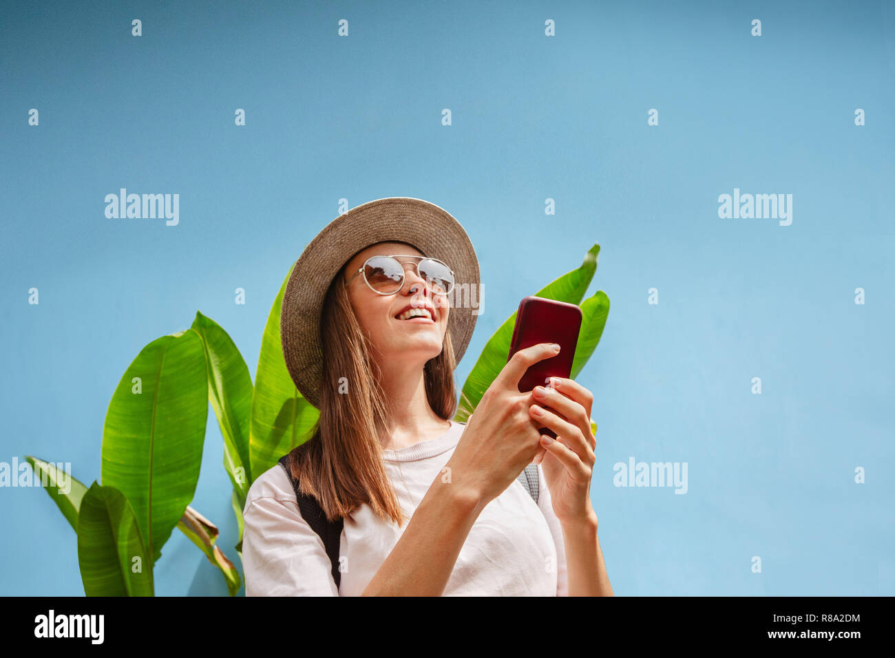 Excited young female on vacation uses smartphone Stock Photo