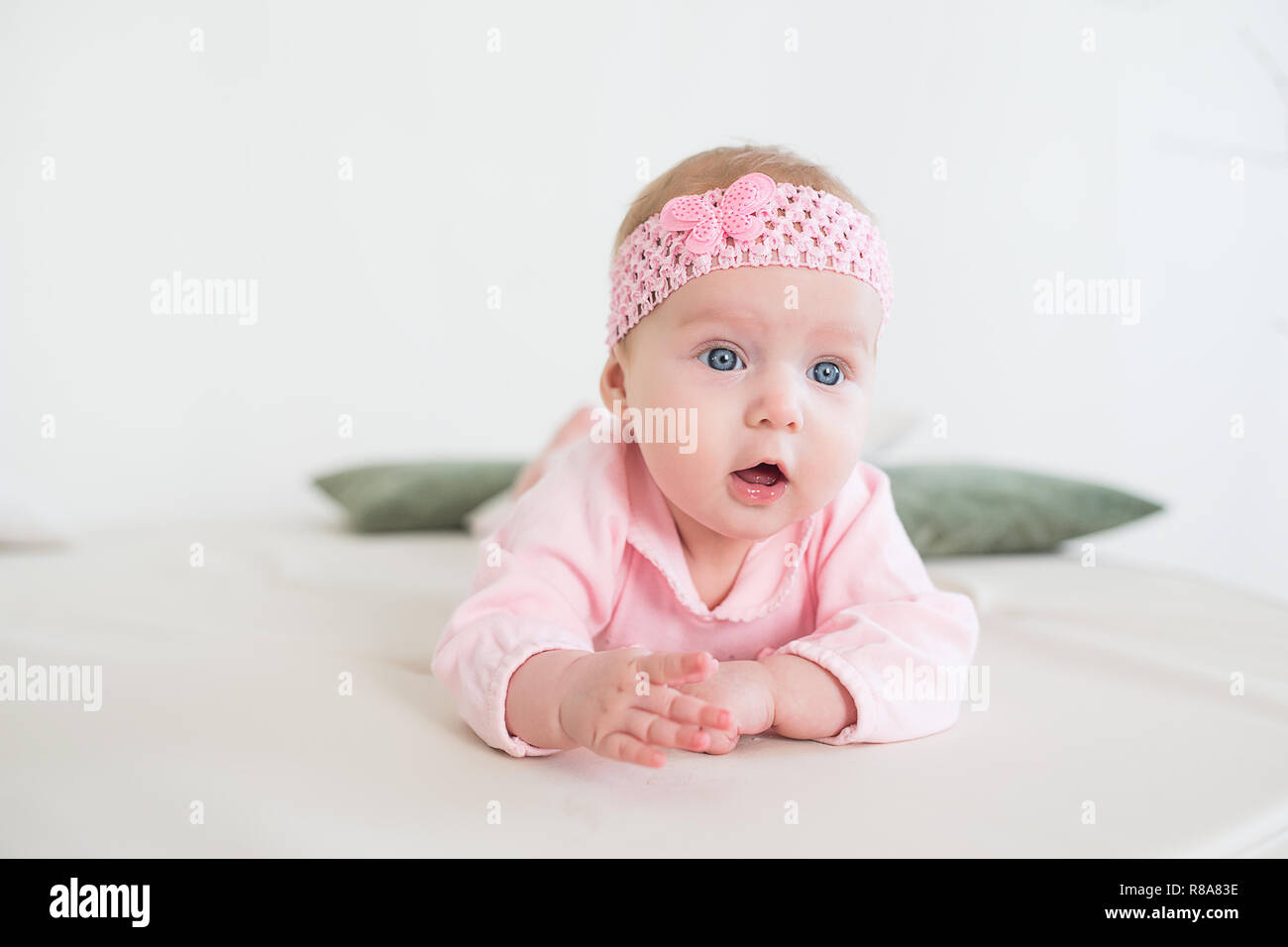 baby lying on his stomach on the floor and looking forward. Beautiful baby girl in pink. Stock Photo