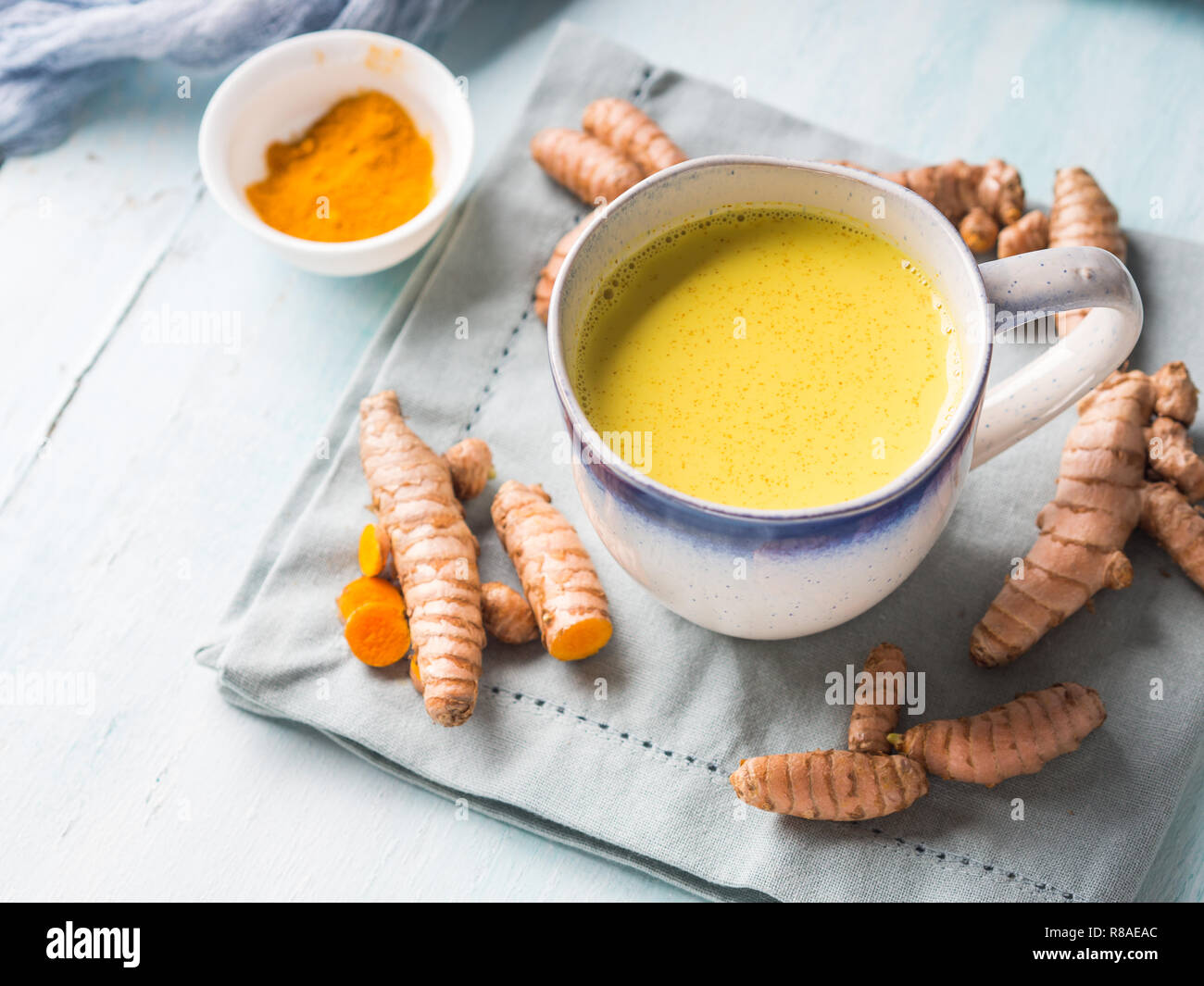 Golden turmeric coconut milk drink in mug on pastel background. Healthy
