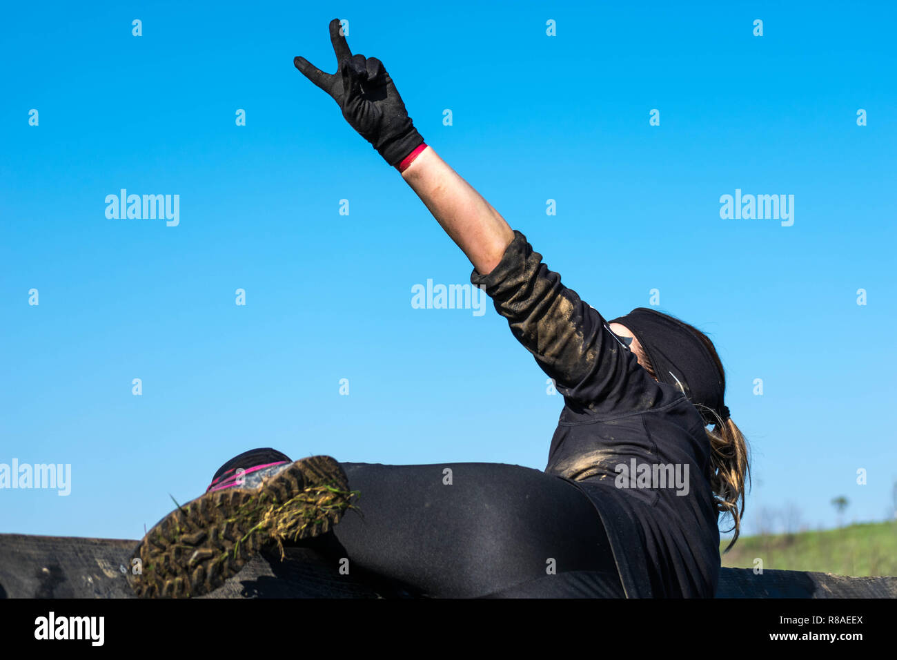 sportwoman in a extreme racing making the victory symbol with her hand. Success, effort and women power. Equality of gender in sports. Stock Photo