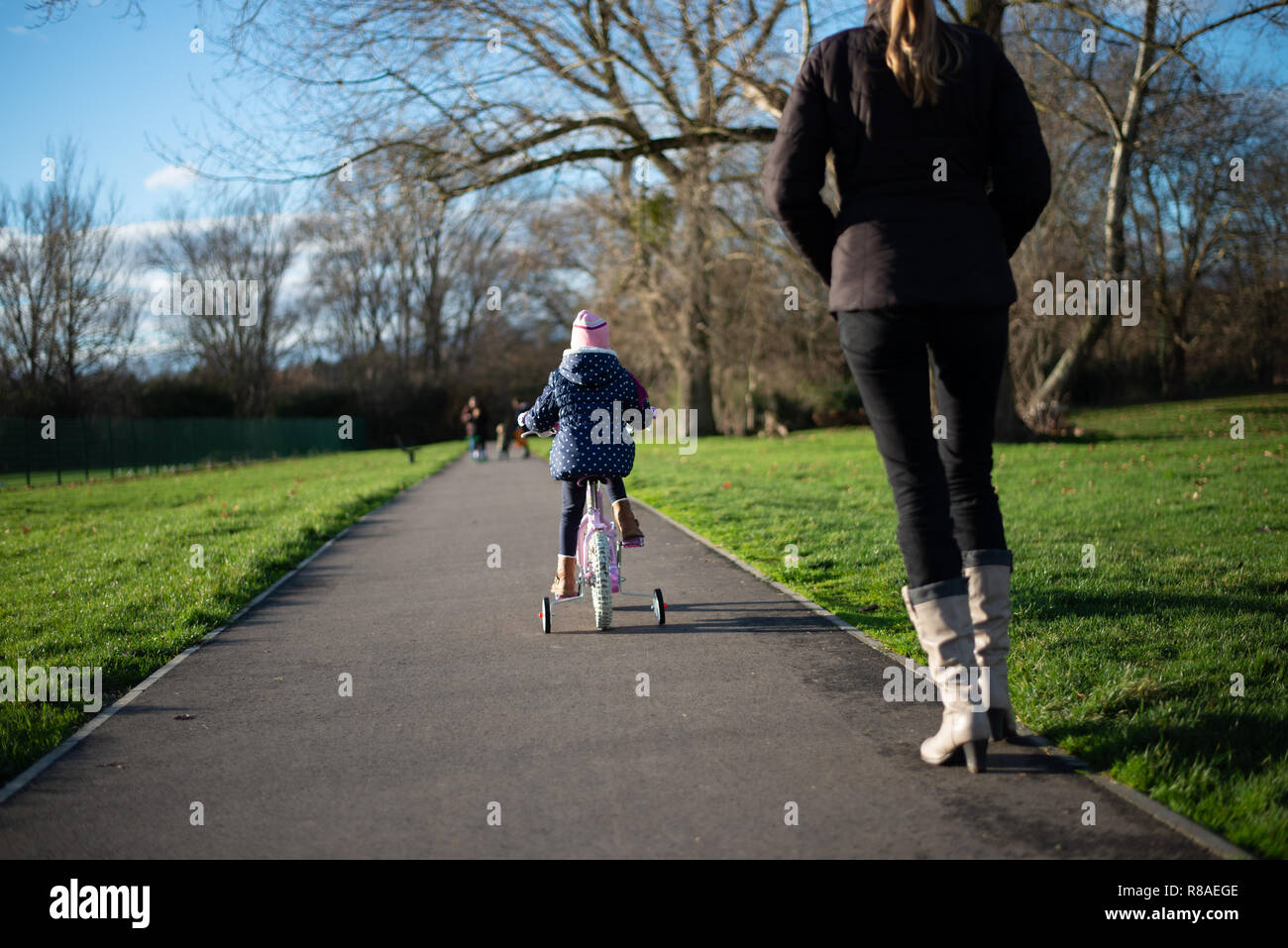 caucasian pre school age girl on the pushbike followed by her mother Stock Photo