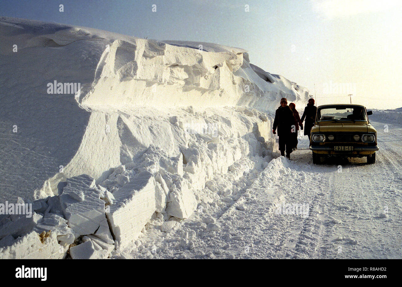 Person next to a car on a meter-high snowdrift on the road F96