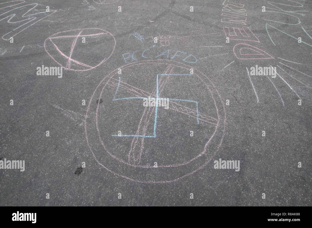 Munich, Bavaria, Germany. 14th Dec, 2018. At the conclusion of the artistic action of sketching slogans and designs on the ground, police alleged that the group used the illegal swastika and received a criminal complaint. Despite being crossed out and an anti-AfD message written with it, police allege it was not clear. Writing the swastika crossed out to express anti-Nazi views is protected in Germany and even the radical-right Pegida uses the Swastika in their logo with no consequence. As part of a worldwide action, 100 students and concerned citizens participated in a climate strike Stock Photo