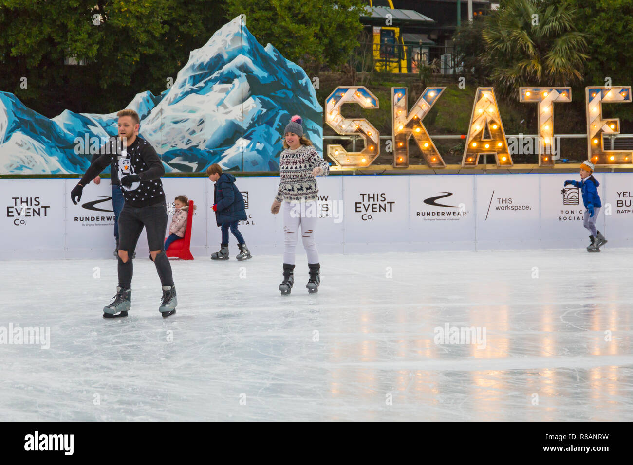 Bournemouth, Dorset, UK. 14th December 2018. Visitors have fun ice skating on the outdoors temporary ice rink in Bournemouth Gardens on a bitterly cold overcast day. Couple skate in their Christmas jumpers. Skating in festive jumper - very appropriate with snowman and snow, being the weather forecast for next few days!  Credit: Carolyn Jenkins/Alamy Live News Stock Photo