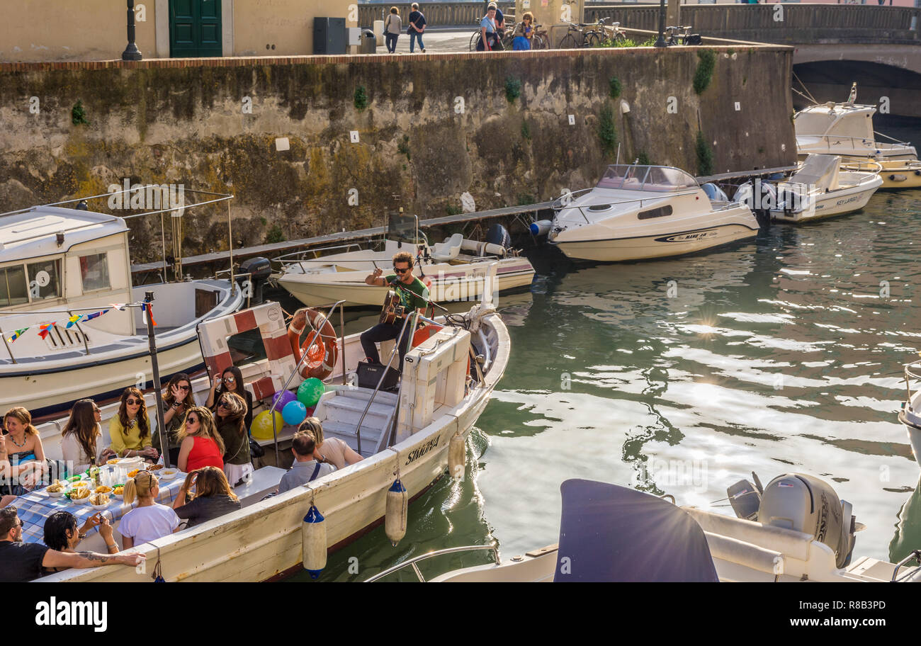 Tourists on the boat in the Livorno Canal, Venice district. The Venice quarter is the most charming and picturesque part of the city of Livorno in Tus Stock Photo