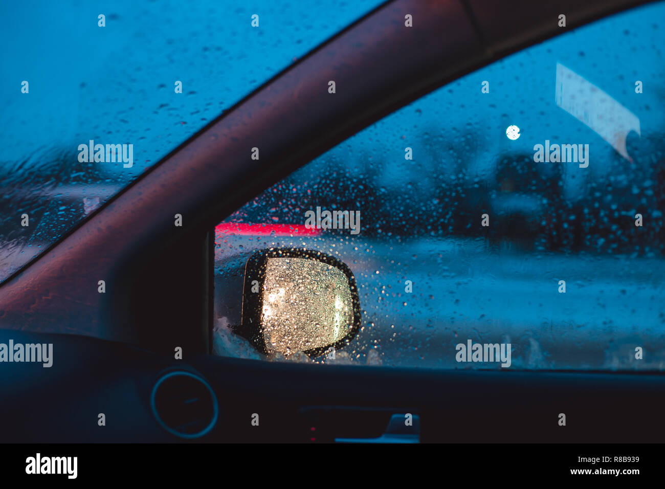 The light of car headlights is reflected in the side mirror of the car. Car traffic winter morning. Stock Photo