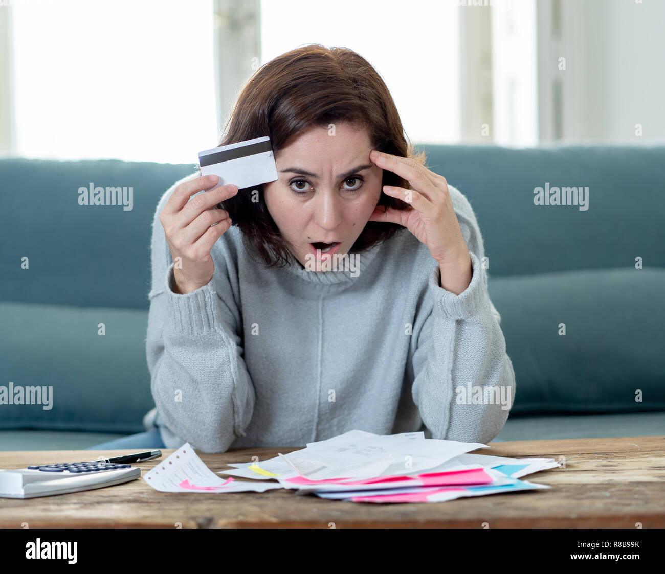 Young attractive woman having trouble with card payments and home finance worried calculating accounting costs charges taxes in financial problems Sho Stock Photo