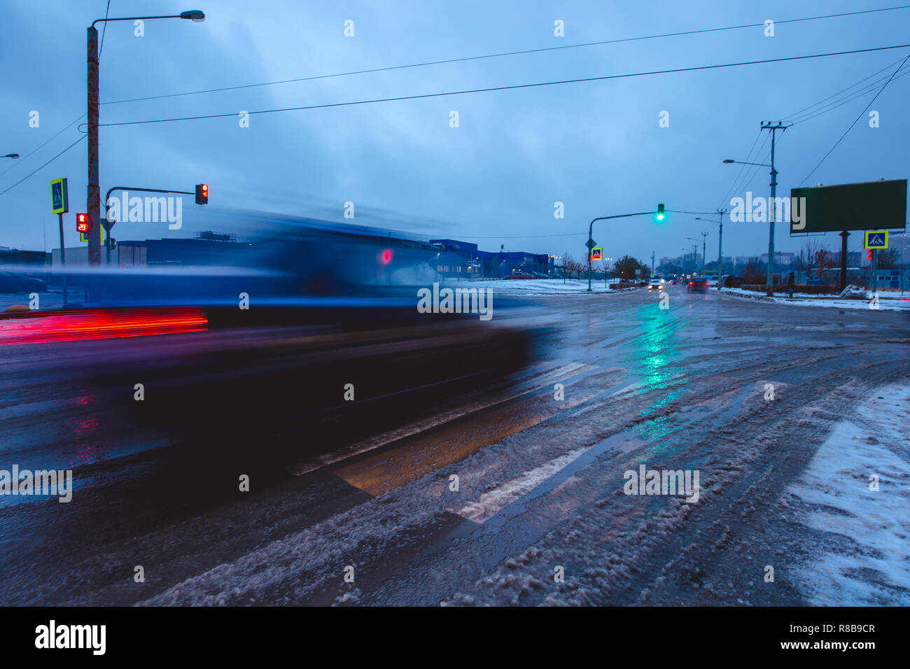 Wide angle shot of a car in motion on a city street in winter evening. Traffic moving cars in cold weather. Stock Photo