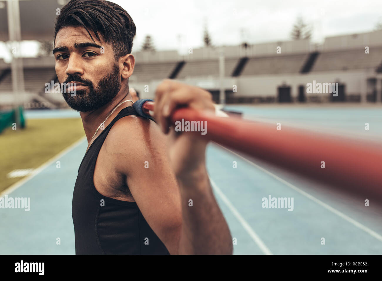 Close up of an athlete standing on track holding a javelin on his