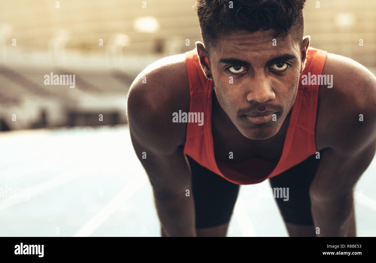 Athlete relaxing after a run standing on the track. Sprinter standing on running track with his hands on knees. Stock Photo